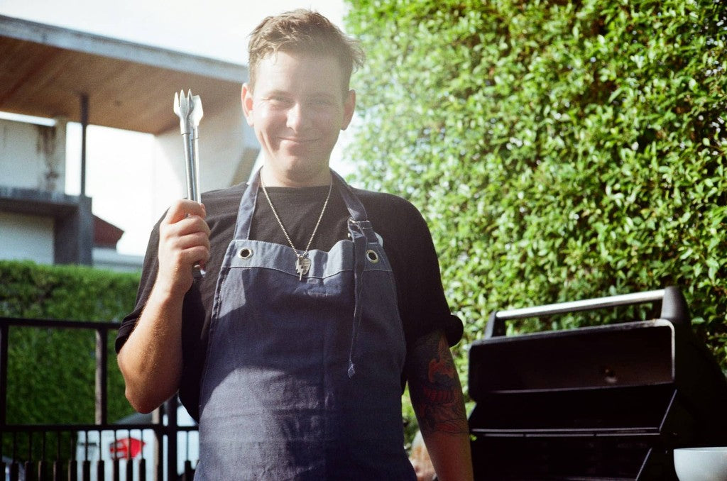 Person ved grill på en solrik terrasse